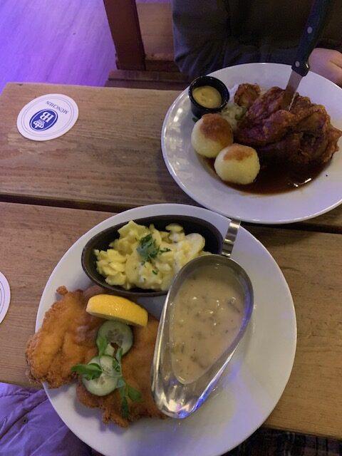 Schweinshaxe, potato dumplings and schnitzel on a table in a German beer hall in Berlin